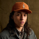 Person wearing orange corduroy Cactus Tacos hat with cactus embroidery, denim jacket, and plaid shirt.