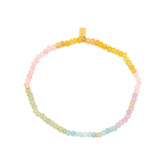 Ombre rainbow bead stretch anklet with pink to yellow beads and small gold spacers on white background
