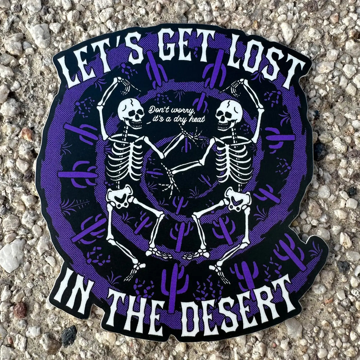 Let's Get Lost In The Desert sticker with two skeletons dancing inside a purple circular desert scene.