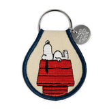 Snoopy resting on a red doghouse patch with beige background and navy edging attached to a key ring