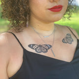 Monarch butterfly temporary tattoo spanning the chest above the neckline