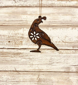Rusty metal quail shaped ornament with a floral cutout hanging by a string.