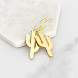 Gold elongated cactus hoop earrings with a smooth finish on a light background.