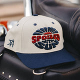 Spoiled With Sun two tone hat with blue sunburst embroidery and red lettering on beige crown