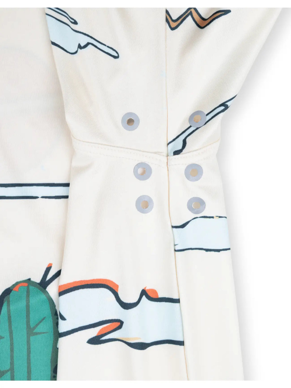Close-up of a white garment with a desert print and silver snap buttons along the placket
