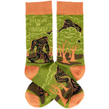 Believe in Yourself socks with orange cuffs green body and a forest scene with a bigfoot silhouette.