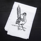 White tea towel on a dark surface featuring a bold roadrunner illustration and Counter Couture text