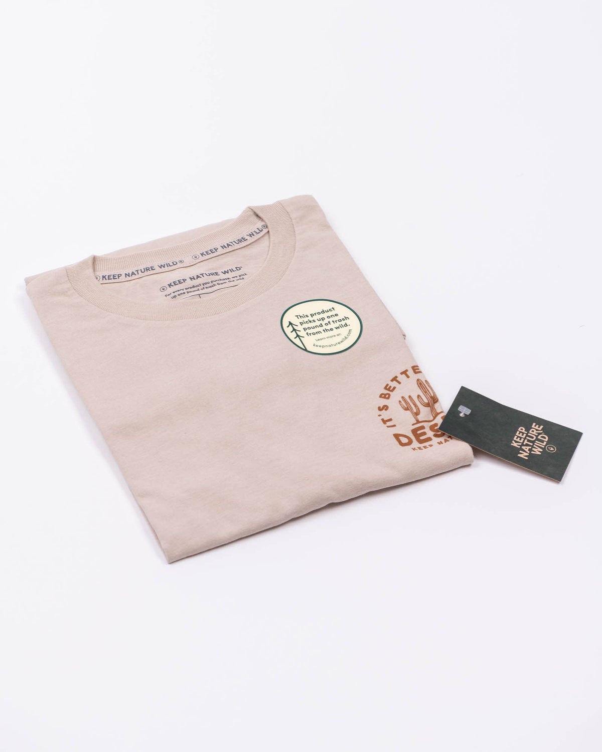 Heather tan tee folded with a large front desert graphic and a black hang tag attached.