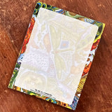 Dragonfly themed notepad placed on a brightly patterned notebook.