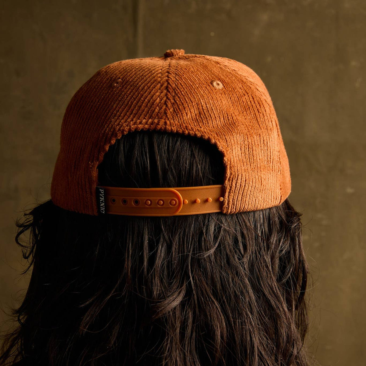 Rear close-up of orange corduroy Cactus Tacos hat showing seam and hair beneath.