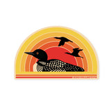 Retro loon sticker featuring a black loon silhouette against a sunset with orange red center and yellow arcs.