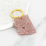 Acrylic Arizona keyring in pink glitter with a gold ring and heart cutout