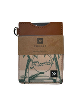 Florida Palms vertical wallet with palm leaf patterned fabric and brown leather top, shown on wood surface.