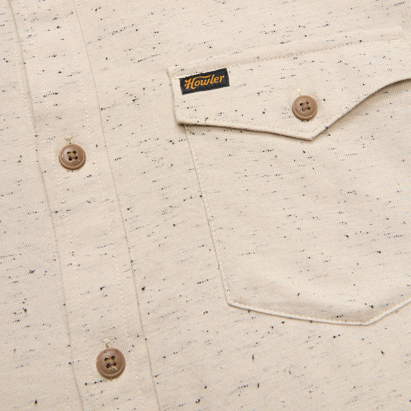 Speckled sand shirt pocket with button and Howler label close up