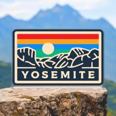 Yosemite National Park Sunset sticker affixed to a laptop with a mountainous backdrop