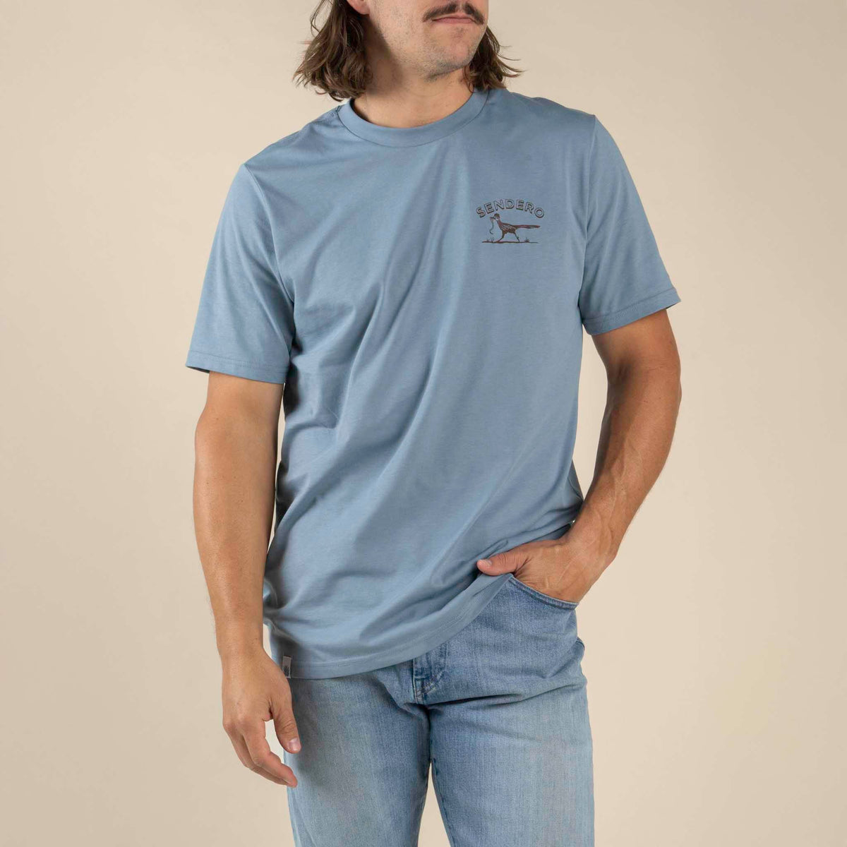 Front view of a light blue Desert Runner T Shirt with a small chest logo of a bird