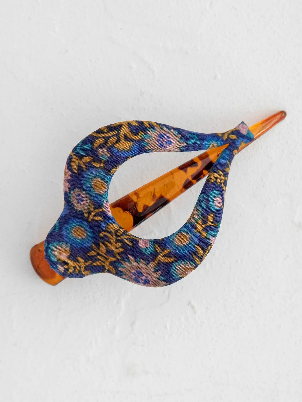 Close up of a blue floral boho hair clip with an orange end