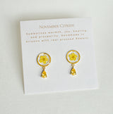 November Citrine birthstone earrings featuring pressed yellow flowers in gold circular settings with a matching teardrop charm on a card