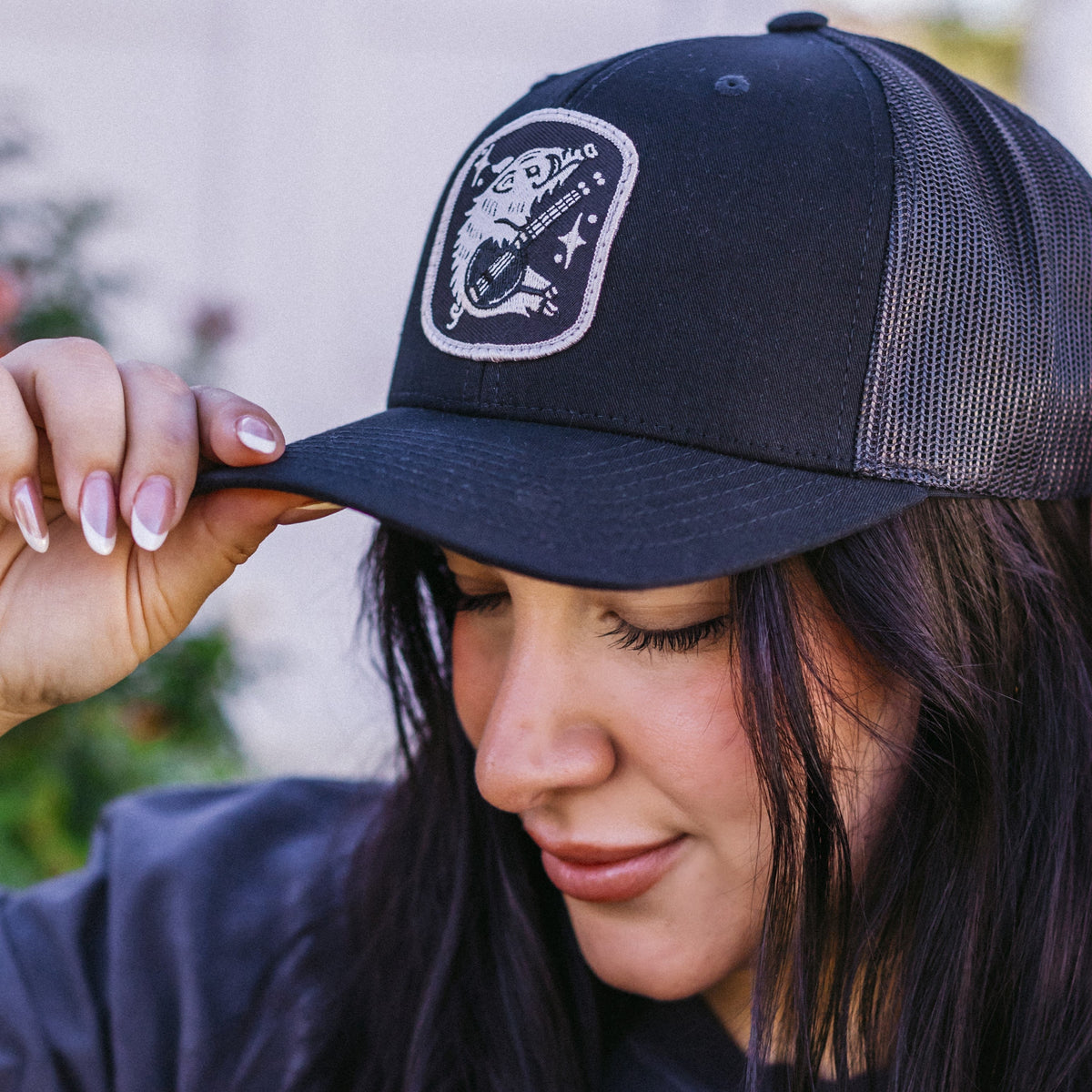 Close-up of a navy Pickin' Javelina Trucker hat being adjusted by hand, with a stitched front patch.