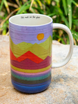 Purple mug with a colorful rainbow mountain design and the phrase This must be the place around the rim.