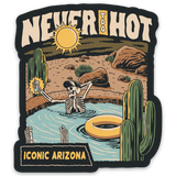 Never Too Hot sticker design with bold Never Too Hot lettering over a desert scene with sun, rocks and cacti.
