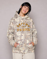 Front view of Defend the Parks Bear Hoodie in beige camouflage with orange logo on the chest worn by a model