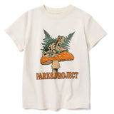 Cream colored kids tee with a frog perched on an orange mushroom among fern leaves and Parks Project branding.