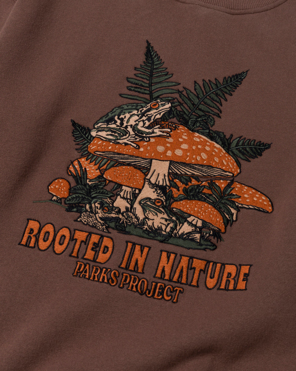 Embroidered brown Parks Project Rooted in Nature Ferns Crewneck with orange mushrooms and fern leaves.
