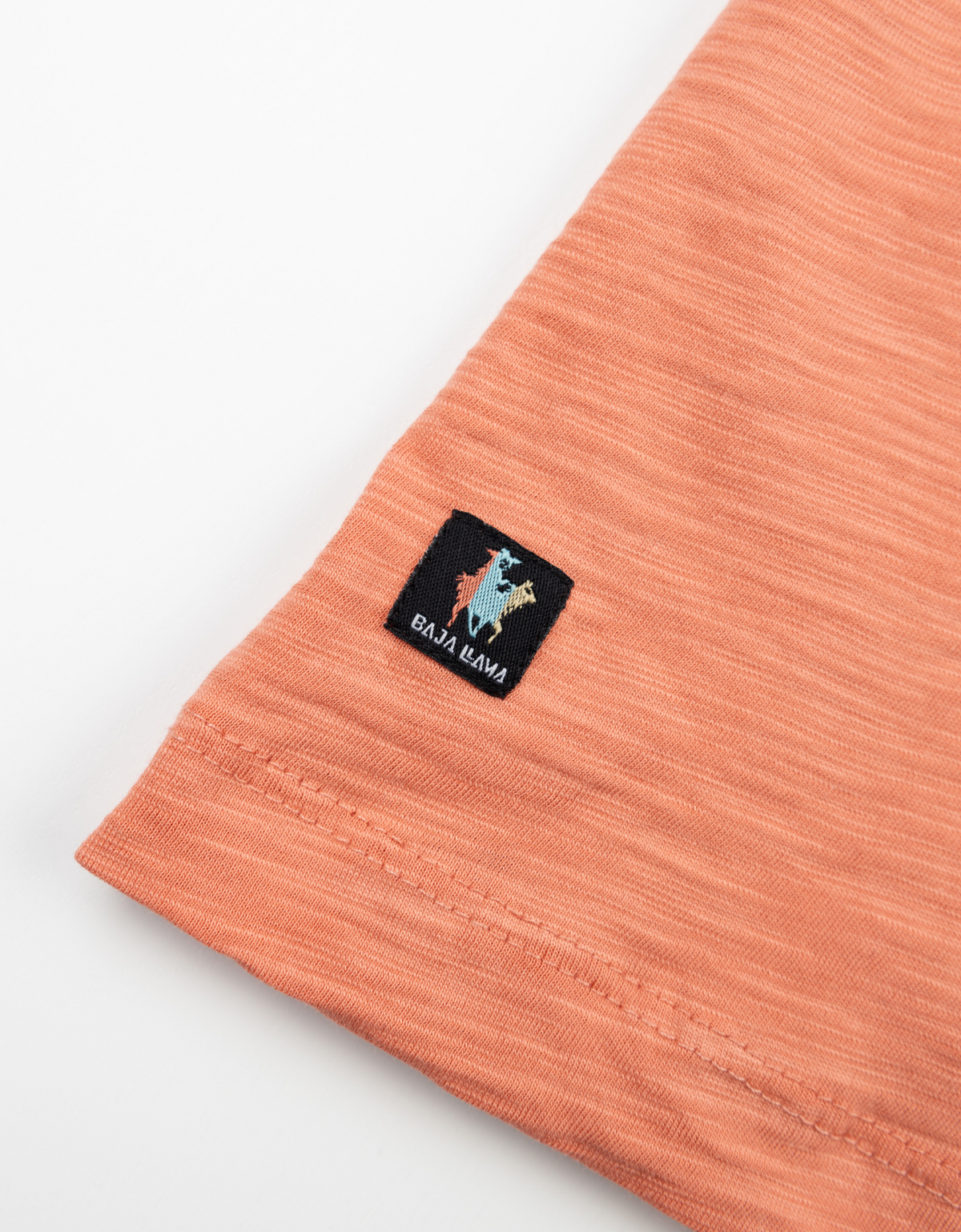 Close up of coral Slub Pima Pocket Tee sleeve with a Baja Lava label patch