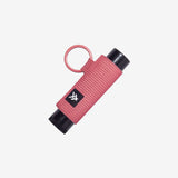 Coral pink woven lip balm holder with black ends and a pink ring.