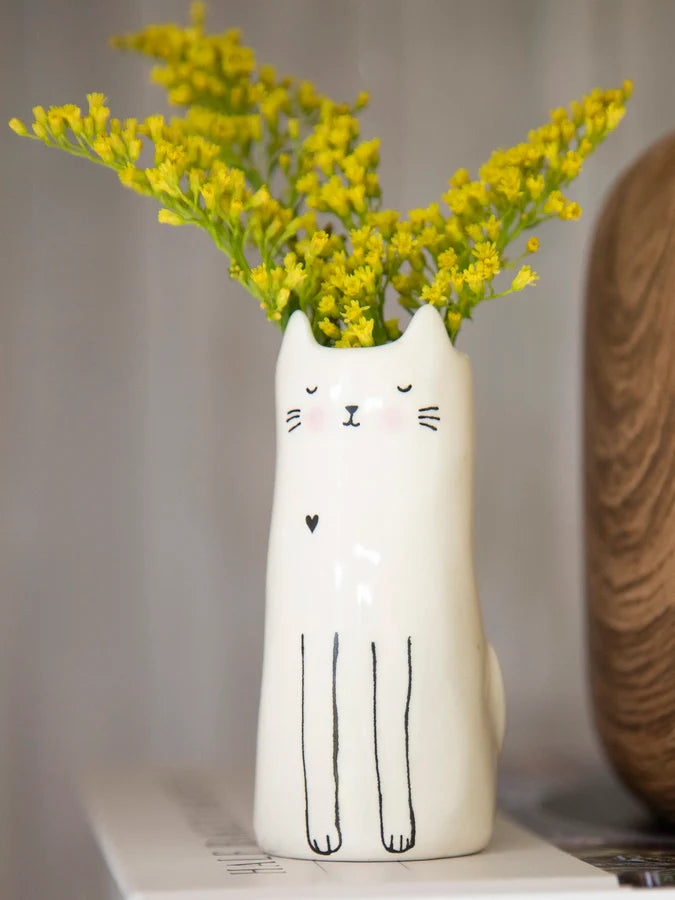 White cat shaped bud vase filled with bright yellow blooms