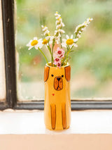 Yellow dog shaped ceramic bud vase filled with white daisies and small pink flowers