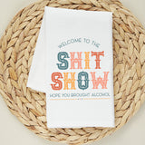 White tea towel printed with the colorful text Welcome to the Shit Show