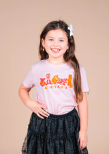 Smiling girl wearing a pink State Forty Eight Desert Divas kids tee with colorful animal illustrations.