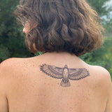 Hawk tattoo with outstretched wings across the upper back.