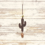 Rusty brown metal desert cactus wind chime with a bead above and a cork weight hanging from a chain.