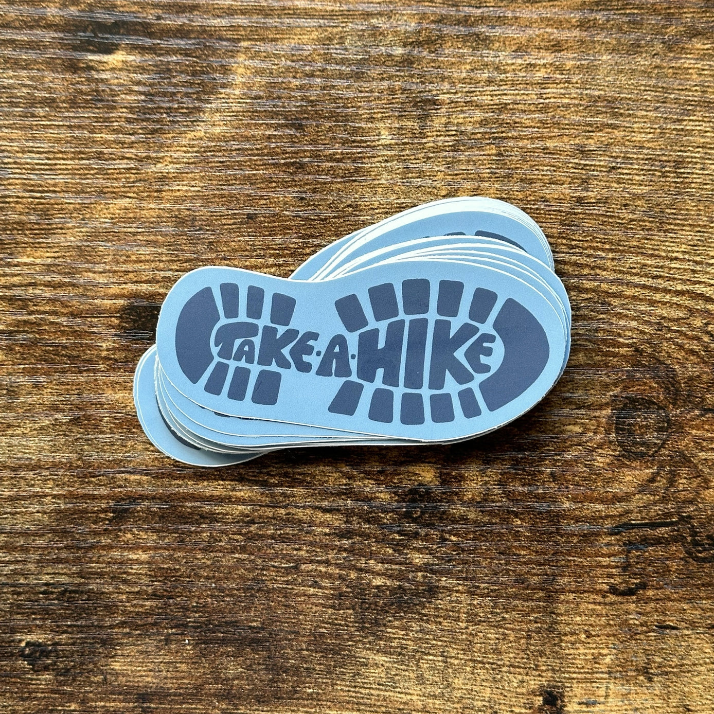 Stack of 'Take a Hike' stickers on a wooden surface