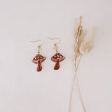 Red mushroom shaped dangle earrings with white detailing on gold hooks
