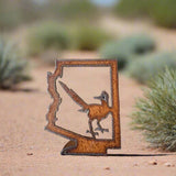 Rusty metal cutout of the Arizona outline with a roadrunner inside the shape.