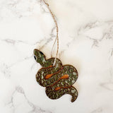 Snake ornament with a green scaly body hanging by jute twine