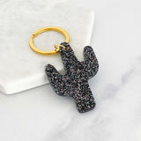 Acrylic cactus shaped keyring with black glitter attached to a gold ring
