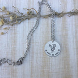 Round silver butterfly pendant necklace with floral accents on the edge of the pendant
