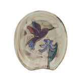 Spoon rest showcasing a purple hummingbird and blue flower on a beige glazed ceramic surface