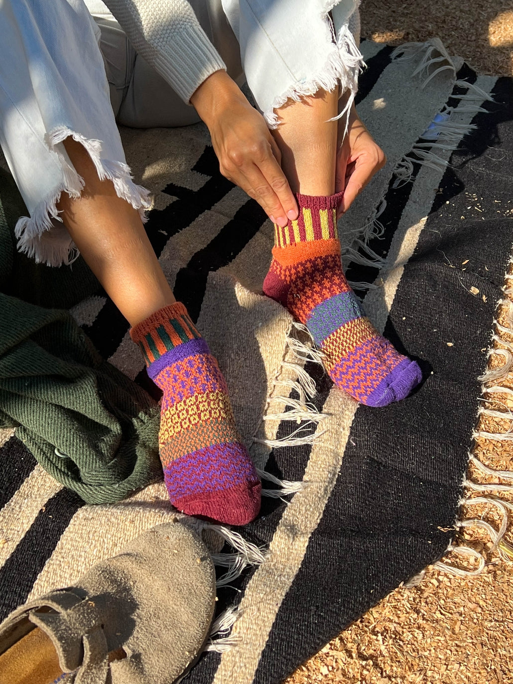 Person wearing multicolor knit ankle socks outdoors showing a vibrant striped pattern.