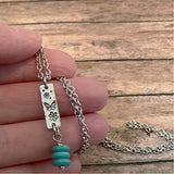 Mini butterfly dangle necklace with a rectangular etched charm and turquoise bead stack on a silver chain.
