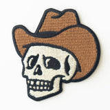 Embroidered cowboy skull patch with a brown hat and black outline