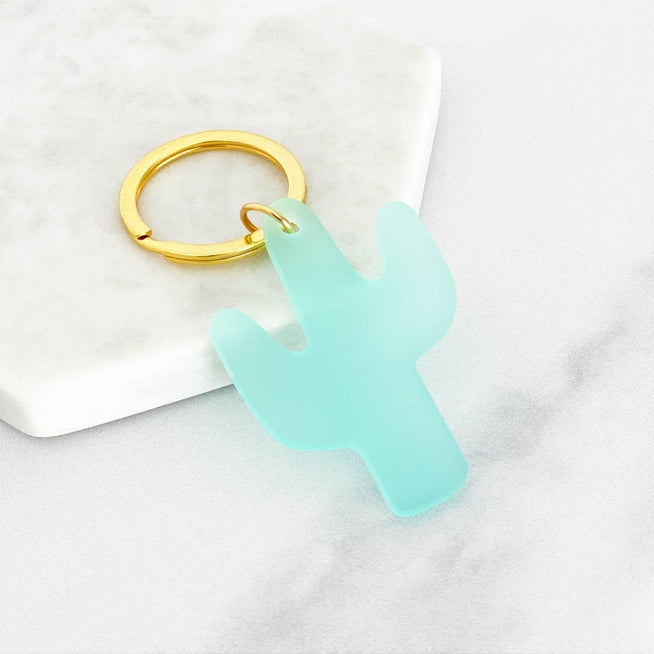 A mint turquoise glitter acrylic cactus keyring on a gold ring
