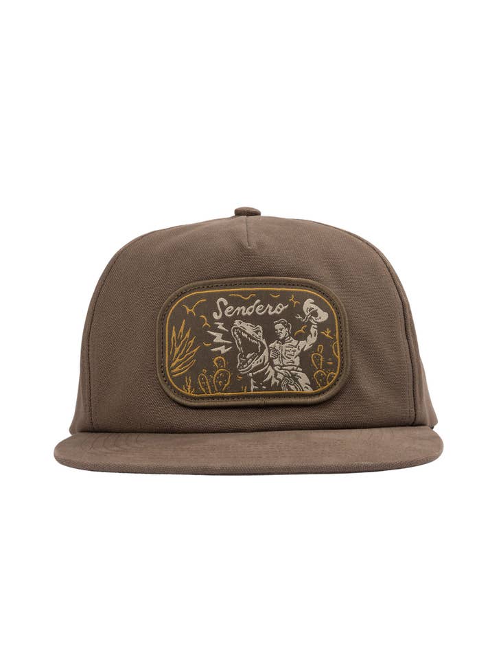 Front view of brown Velociwrangler flatbrim cap featuring the embroidered western patch on the crown