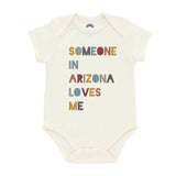 Cream baby onesie with multicolored letters spelling SOMEONE IN ARIZONA LOVES ME