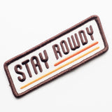 Rectangular embroidered Stay Rowdy patch with white center brown border brown letters and orange underlines